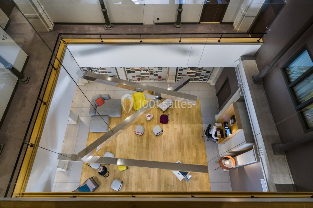 Vue plongeante sur un espace de détente moderne avec canapés, coussins colorés et étagères murales.