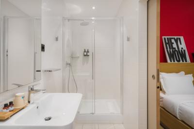 Salle de bain moderne avec murs sombres, douche à l'italienne et vue sur un sauna en bois éclairé.