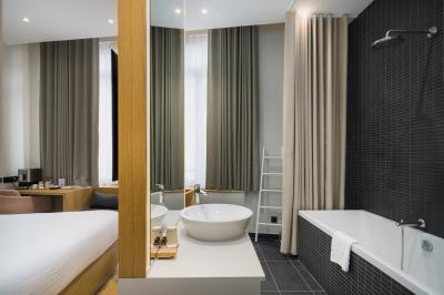 Salle de bain moderne avec murs sombres, douche à l'italienne et vue sur un sauna en bois éclairé.