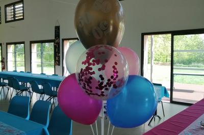 Salle lumineuse avec deux rangées de tables et chaises bleues, grandes fenêtres et portes vitrées sur les côtés.