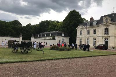 Bouquet de fleurs jaunes et blanches posé sur le capot d'une voiture ancienne noire, sous un ciel bleu.