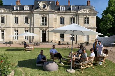 Bouquet de fleurs jaunes et blanches posé sur le capot d'une voiture ancienne noire, sous un ciel bleu.