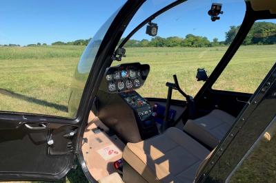 Bouquet de fleurs jaunes et blanches posé sur le capot d'une voiture ancienne noire, sous un ciel bleu.