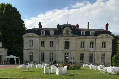 Bouquet de fleurs jaunes et blanches posé sur le capot d'une voiture ancienne noire, sous un ciel bleu.