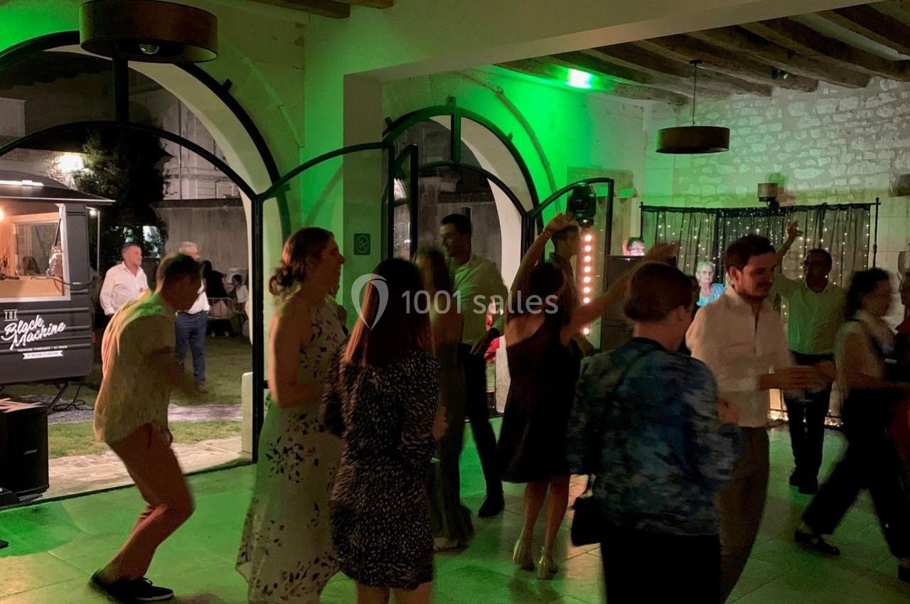 Groupe de personnes dansant dans une salle éclairée de lumières colorées, avec un food truck visible en arrière-plan.