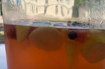 Bouquet de fleurs jaunes et blanches posé sur le capot d'une voiture ancienne noire, sous un ciel bleu.
