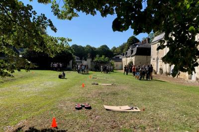Bouquet de fleurs jaunes et blanches posé sur le capot d'une voiture ancienne noire, sous un ciel bleu.