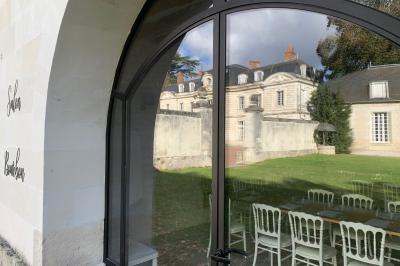 Bouquet de fleurs jaunes et blanches posé sur le capot d'une voiture ancienne noire, sous un ciel bleu.