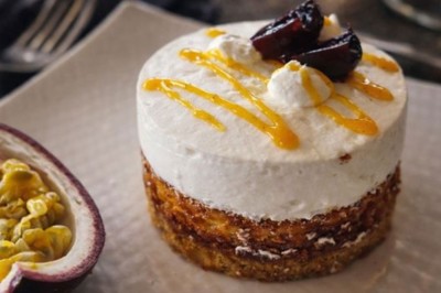 Tranche d'ananas grillée sur un biscuit, garnie de glace vanille, zestes de citron et piments rouges décoratifs.