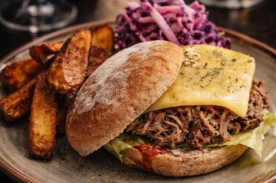 Tranche d'ananas grillée sur un biscuit, garnie de glace vanille, zestes de citron et piments rouges décoratifs.