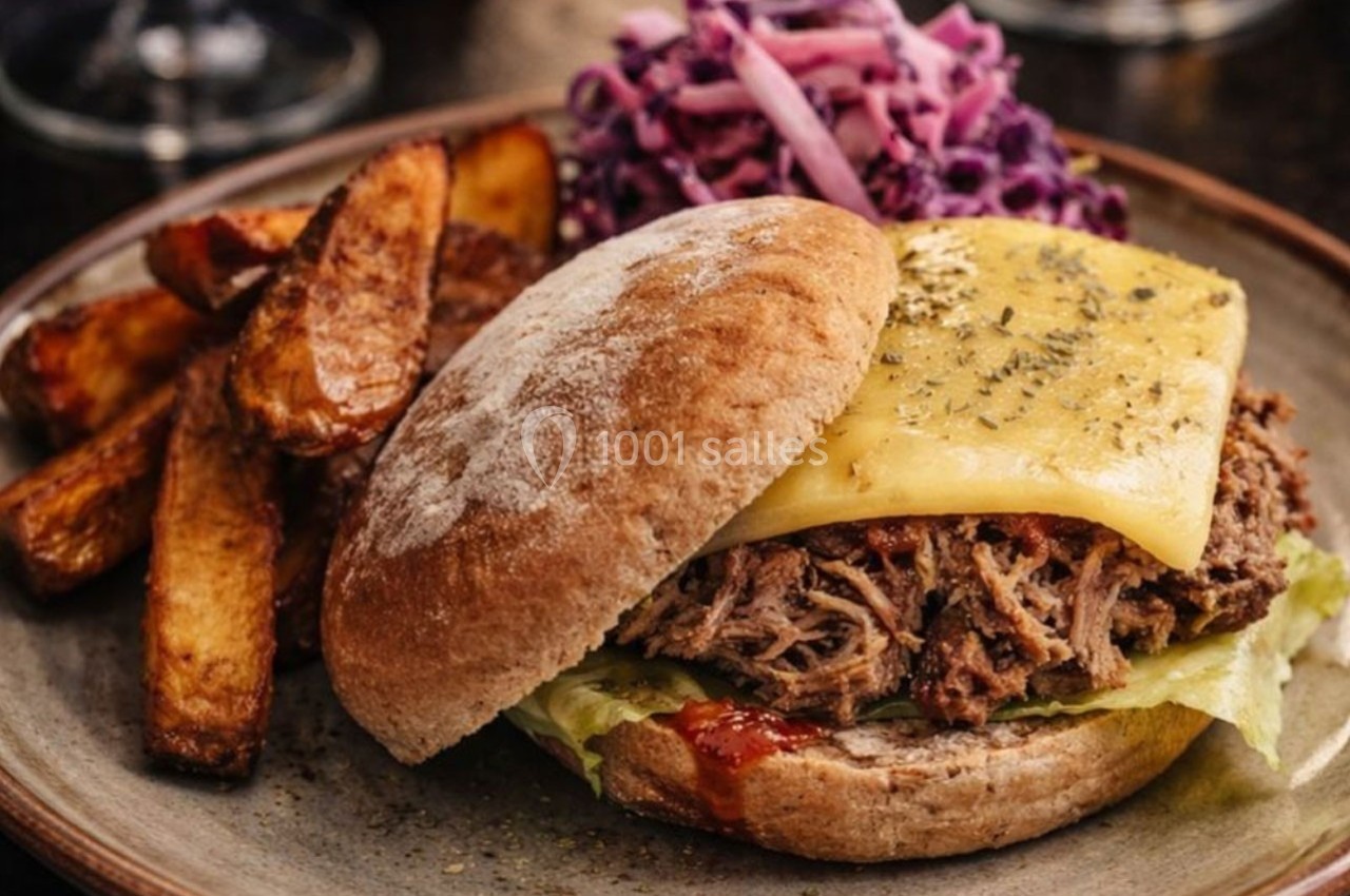 Burger au porc effiloché avec fromage fondu, accompagné de frites et de salade de chou rouge sur une assiette.