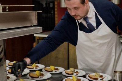 Tranche d'ananas grillée sur un biscuit, garnie de glace vanille, zestes de citron et piments rouges décoratifs.