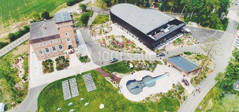 Vue aérienne d'un domaine avec un bâtiment en forme de guitare, un jardin aménagé et une piscine en forme de violon.