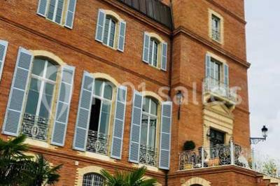 Maison moderne à deux étages avec façade en bois, terrasse et jardinières fleuries sur une allée pavée.