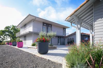 Maison moderne à deux étages avec façade en bois, terrasse et jardinières fleuries sur une allée pavée.