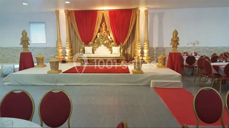 Décor de scène avec trône doré, rideaux rouges, ornements dorés et chaises rouges disposées en avant-plan.