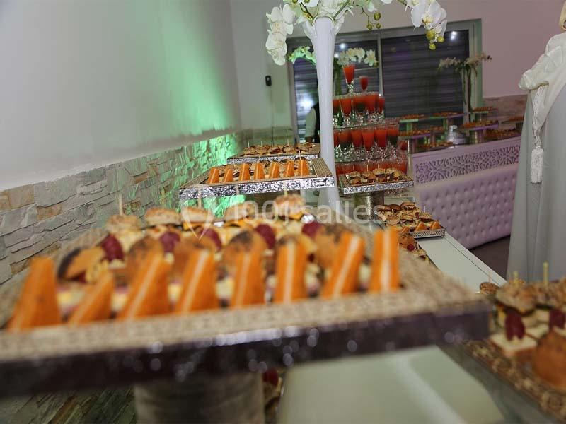 Plateaux de petits fours variés disposés sur une table lors d'une réception avec une décoration élégante.