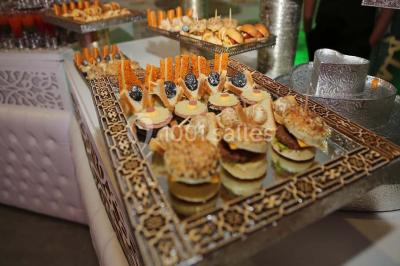 Plateau de petits fours variés présentés sur un support décoratif en métal lors d'un buffet.