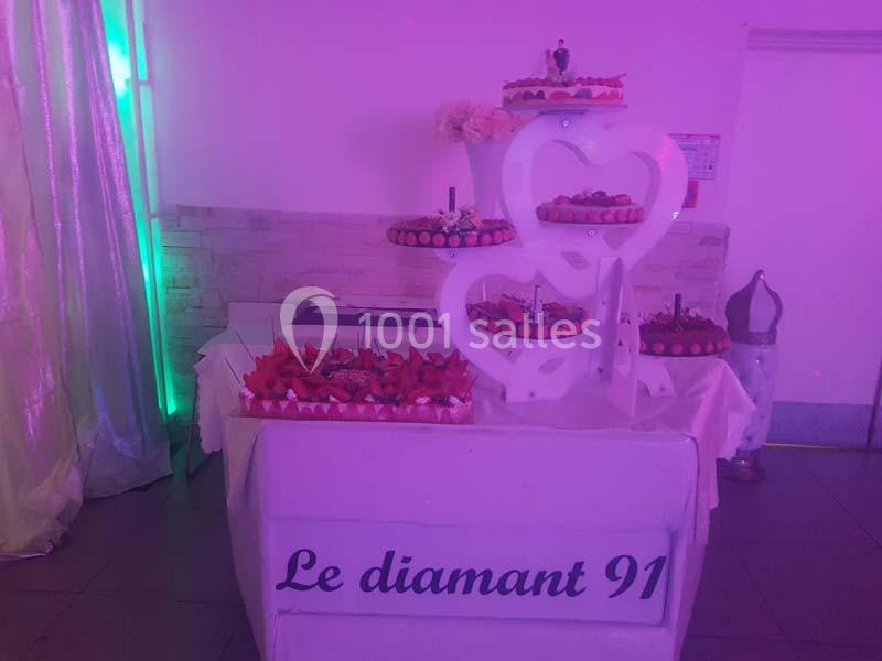 Présentoir de gâteaux décorés sur plusieurs étages avec des cœurs blancs, éclairage rose en arrière-plan.