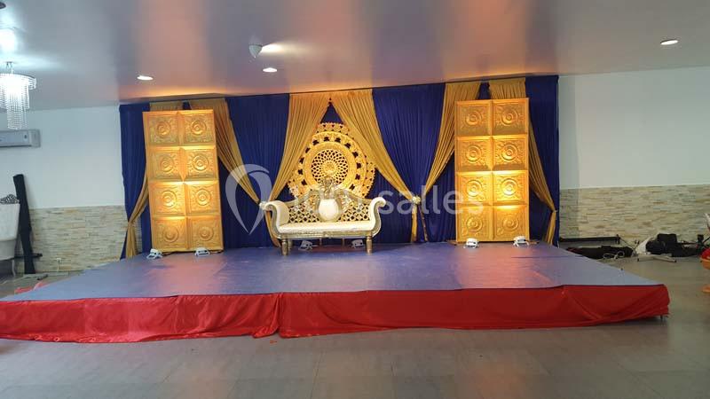 Scène décorée avec un canapé blanc, des rideaux bleus et dorés, et des panneaux lumineux ornés de motifs.