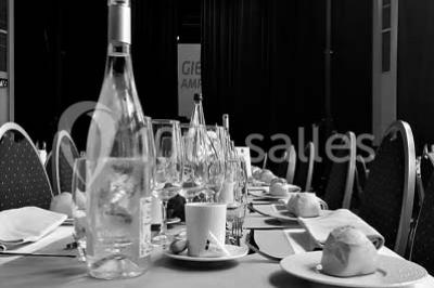 Salle de réception lumineuse avec tables hautes, décor floral et éclairage coloré.