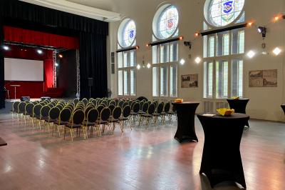 Salle de réception lumineuse avec tables hautes, décor floral et éclairage coloré.