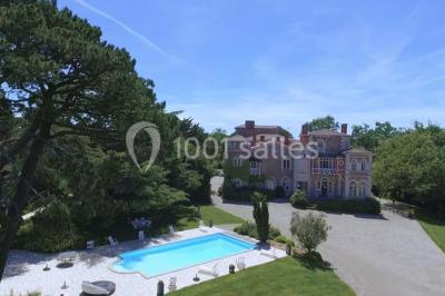 Table en bois dressée avec vaisselle, verres, fruits et fleurs, dans une salle lumineuse au décor chaleureux.