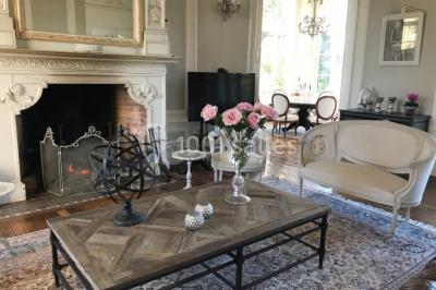 Table en bois dressée avec vaisselle, verres, fruits et fleurs, dans une salle lumineuse au décor chaleureux.