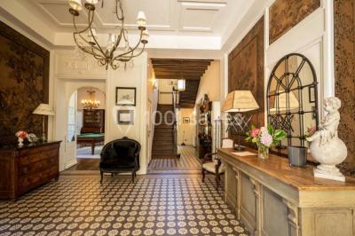 Table en bois dressée avec vaisselle, verres, fruits et fleurs, dans une salle lumineuse au décor chaleureux.