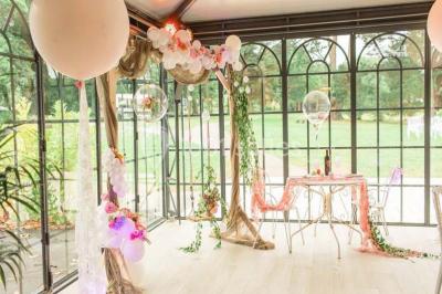 Table en bois dressée avec vaisselle, verres, fruits et fleurs, dans une salle lumineuse au décor chaleureux.