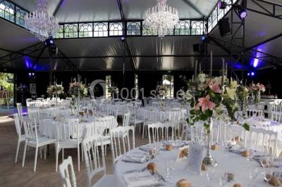 Table en bois dressée avec vaisselle, verres, fruits et fleurs, dans une salle lumineuse au décor chaleureux.