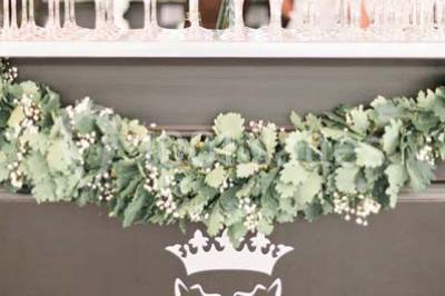 Table en bois dressée avec vaisselle, verres, fruits et fleurs, dans une salle lumineuse au décor chaleureux.