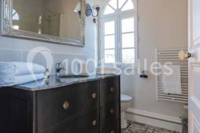 Table en bois dressée avec vaisselle, verres, fruits et fleurs, dans une salle lumineuse au décor chaleureux.