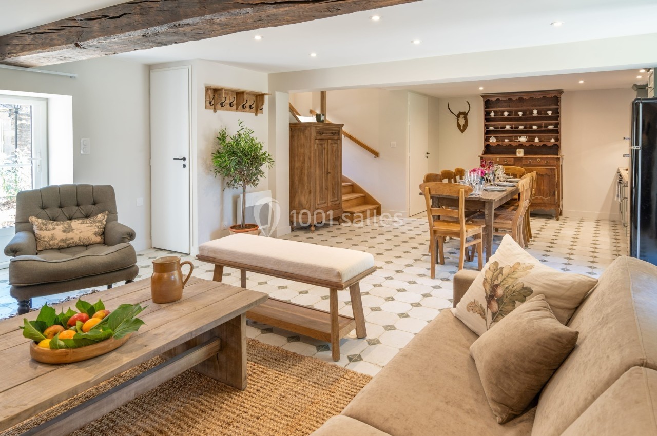 Salon lumineux avec mobilier en bois, table à manger, canapé beige, et décoration rustique dans un intérieur spacieux.