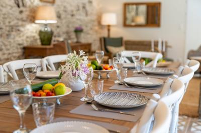 Table en bois dressée avec vaisselle, verres, fruits et fleurs, dans une salle lumineuse au décor chaleureux.