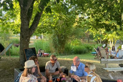 Plateau de fromage avec raisins et pain en arrière-plan, un verre de vin rosé au premier plan.