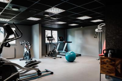 Salle de sport avec vélos d'appartement, tapis de course, ballon d'exercice et équipements de musculation.