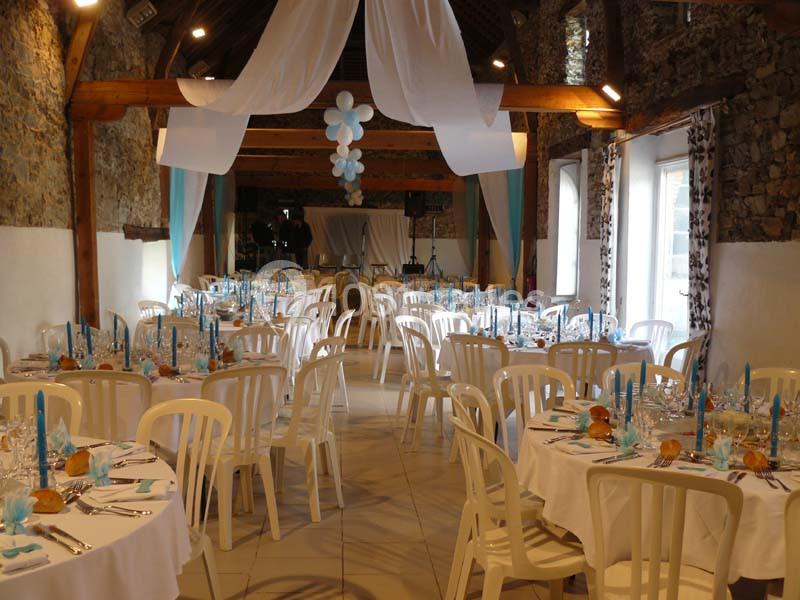 Salle de réception décorée avec des tables rondes dressées, des nappes blanches et des touches de bleu.