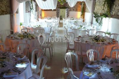 Deux personnes en costume historique s'affrontent à l'épée dans une cour devant un mur en pierre avec des arches.