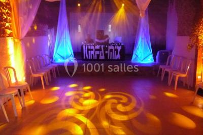 Deux personnes en costume historique s'affrontent à l'épée dans une cour devant un mur en pierre avec des arches.