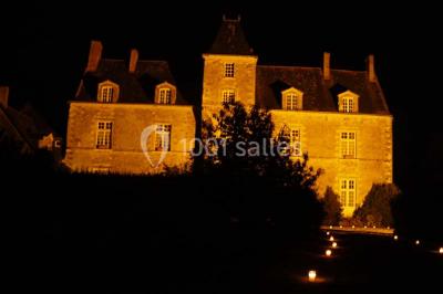 Deux personnes en costume historique s'affrontent à l'épée dans une cour devant un mur en pierre avec des arches.