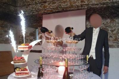 Deux personnes en costume historique s'affrontent à l'épée dans une cour devant un mur en pierre avec des arches.