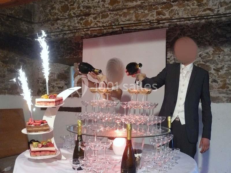 Un couple remplit une pyramide de coupes de champagne, entourée de gâteaux décorés et de feux d'artifice.