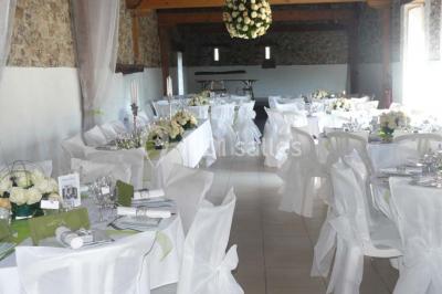 Deux personnes en costume historique s'affrontent à l'épée dans une cour devant un mur en pierre avec des arches.