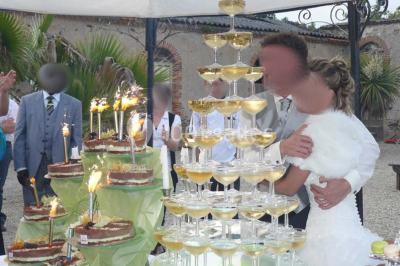 Deux personnes en costume historique s'affrontent à l'épée dans une cour devant un mur en pierre avec des arches.