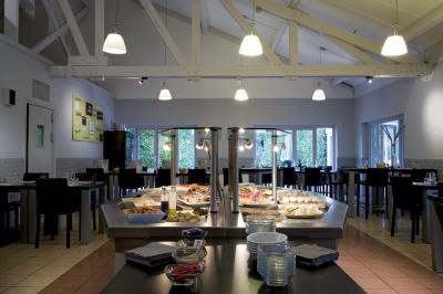 Salle de restaurant moderne avec tables alignées, chaises noires et décoration murale colorée sur le thème de la…