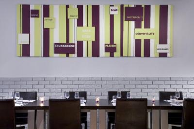 Salle de restaurant moderne avec tables alignées, chaises noires et décoration murale colorée sur le thème de la…