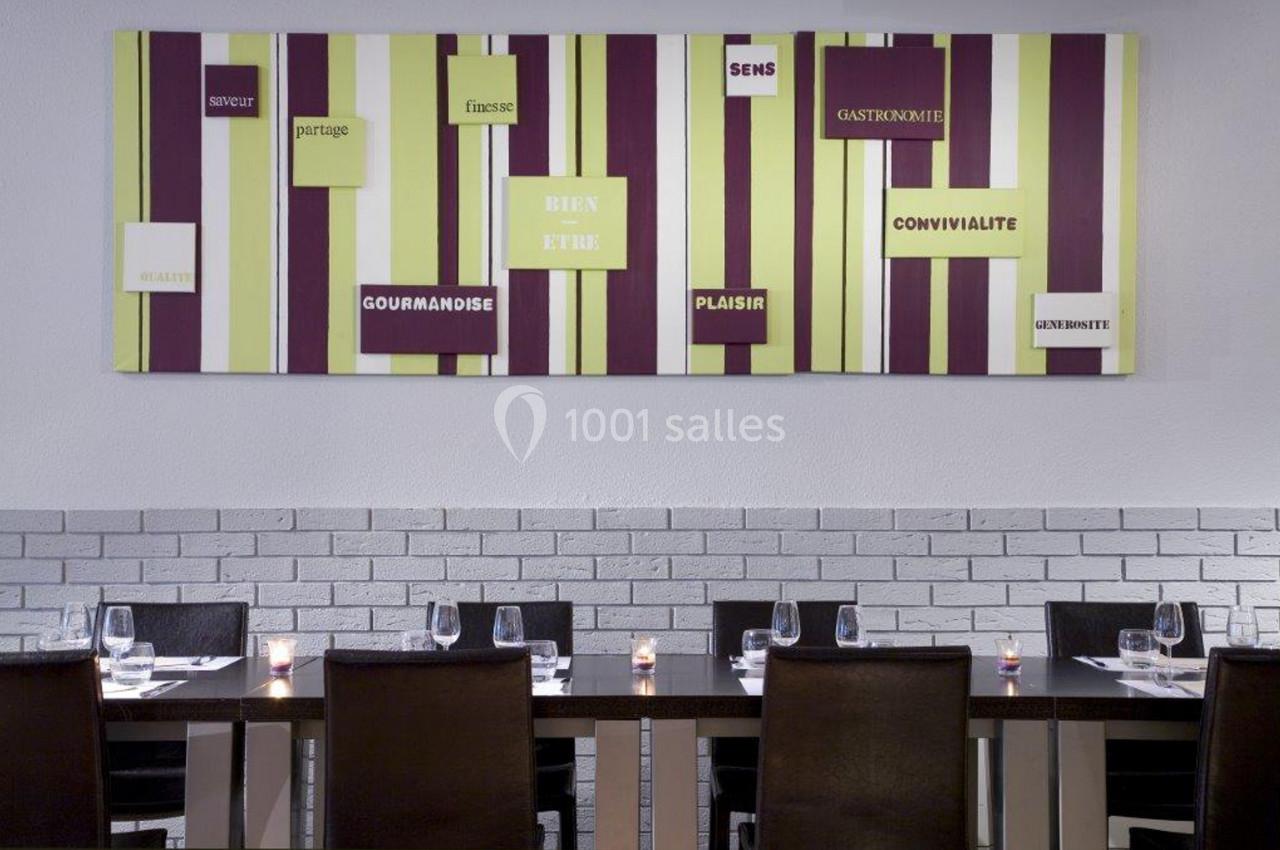 Salle de restaurant moderne avec tables alignées, chaises noires et décoration murale colorée sur le thème de la…