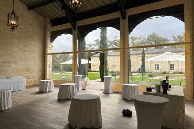 Miniature Préau Orangerie Grande maison en pierre entourée d'un jardin fleuri et arboré, sous un ciel clair.