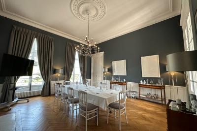 Miniature Salon Gris Privé Grande maison en pierre entourée d'un jardin fleuri et arboré, sous un ciel clair.